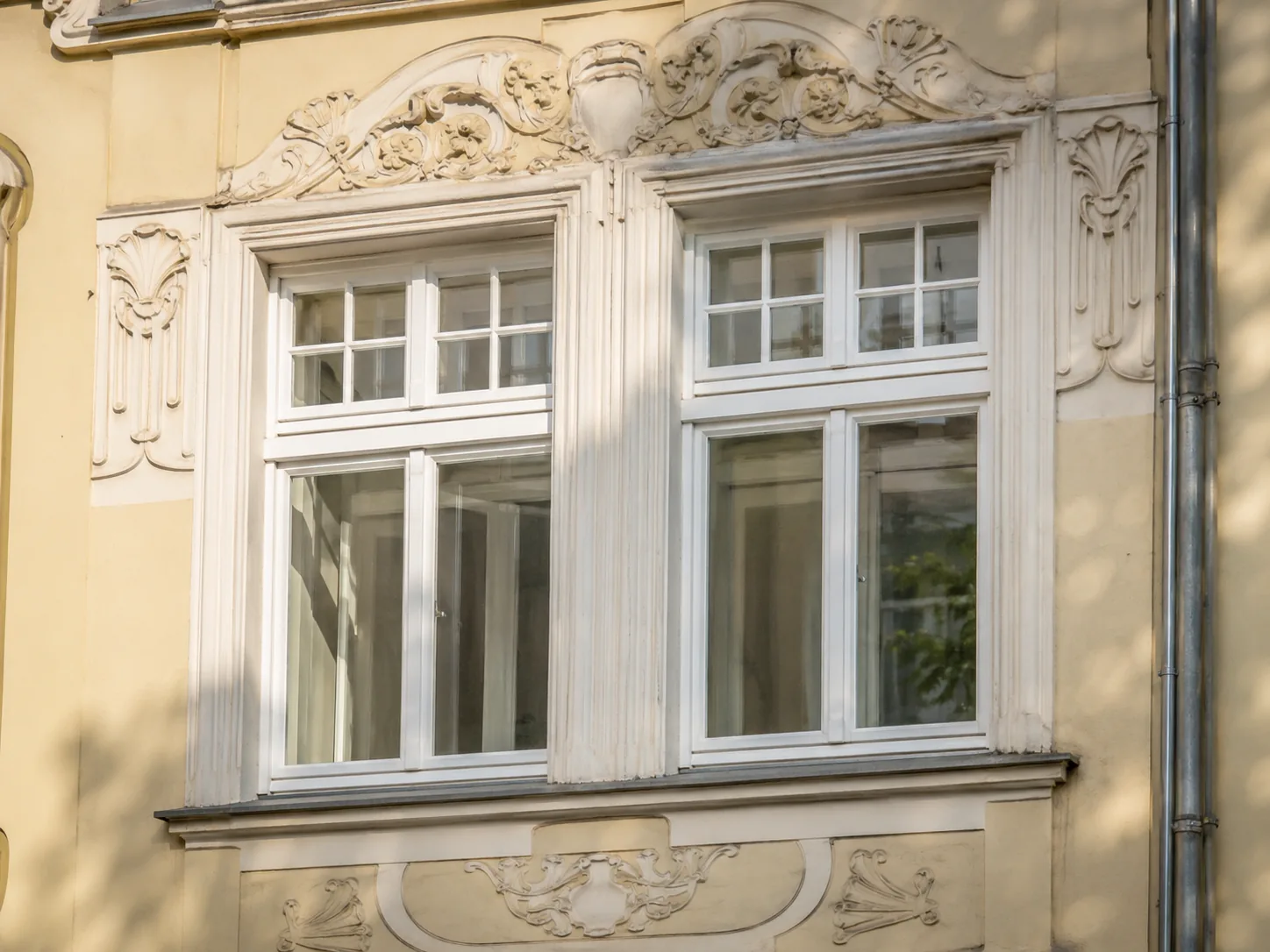 Weiße Kastenfenster in einer Münchner Jugendstilfassade mit Stuckornamenten
